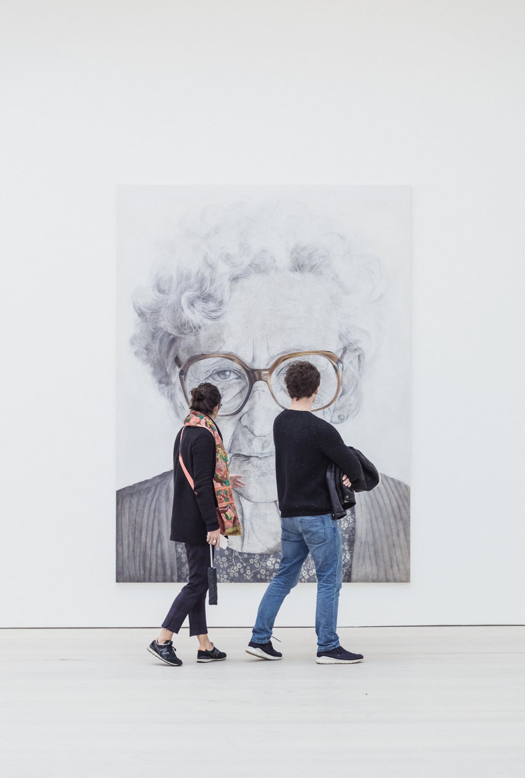 A man and a woman looking at a painting of a lady